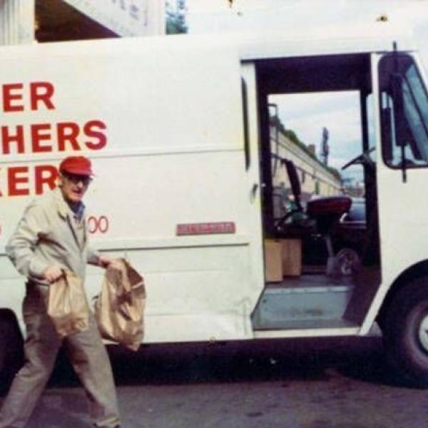 Charlie Brenner in front of a Brenner Brothers delivery truck Charlie holding bags full of goodies in front of a Brenner Brothers delivery truck in Bellevue, ca. 1970-1975