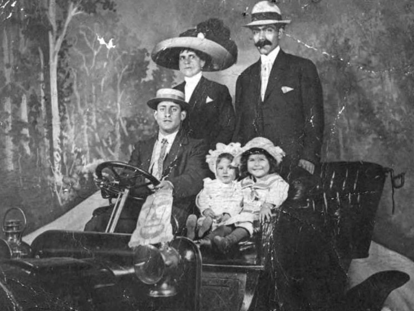 Adatto family including children Albert and Emma Adatto in prop automobile in photographer's studio