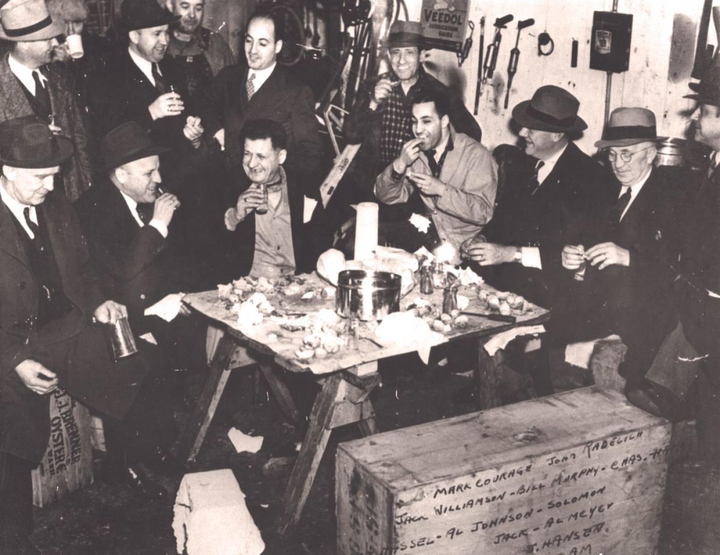 A group of Sephardic men socialize while eating seafood inside the garage of Pacific Fish & Oyster Co. (1940-45)