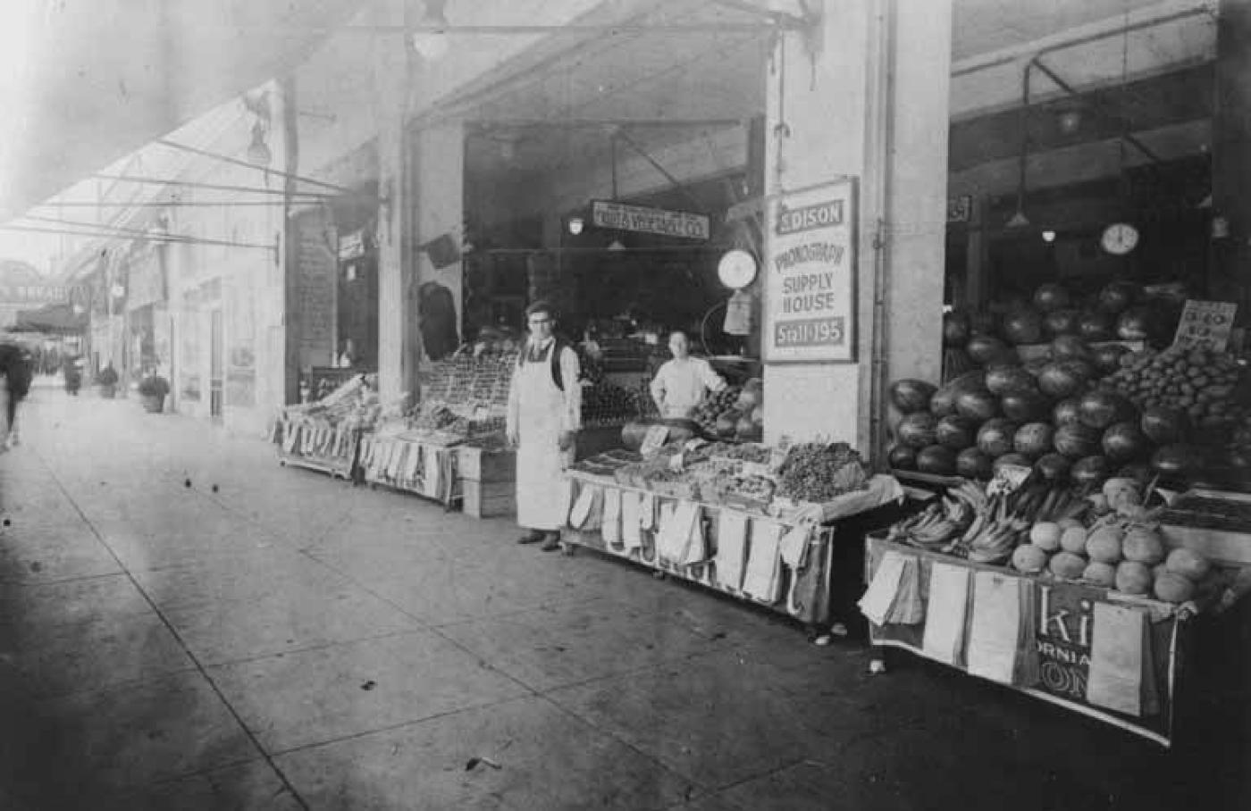 Abe Poll (left) and indentified man at produce stand at Westlake Market, Seattle, Washington, approximately 1915-1925.jpg