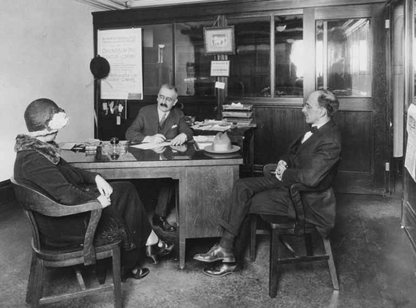 Otto Grunbaum (center) speaking with customers in office at Grunbaum Furniture Co., 6th Ave., Seattle, 1920-1925