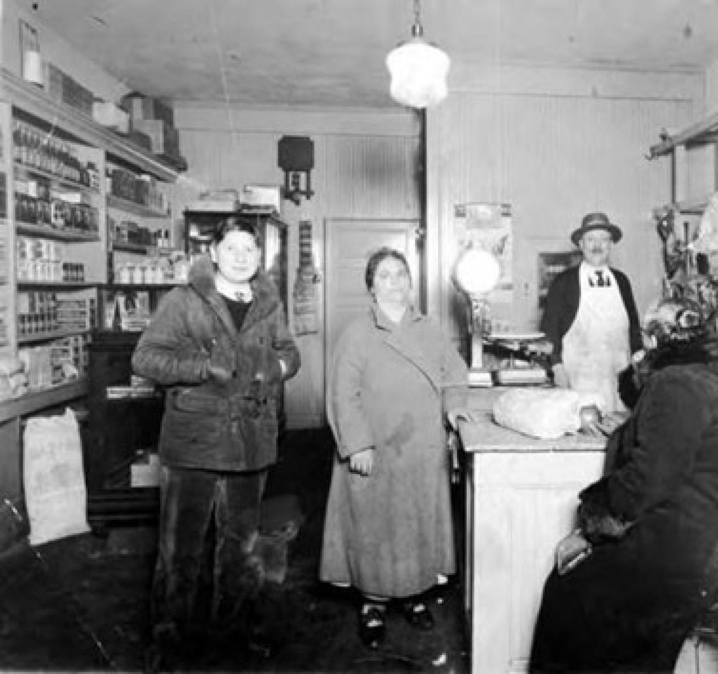 Kutoff Butcher Shop on Yesler Way between 19th and 20th Avenues with Marcus Kutoff (in apron) and son Hyman behind counter and son Alex and two women standing in store, 1930